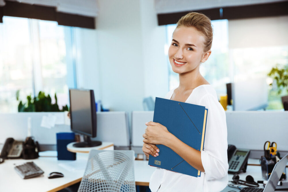Junge Frau im Büro hält eine blaue Ordnungsmappe
