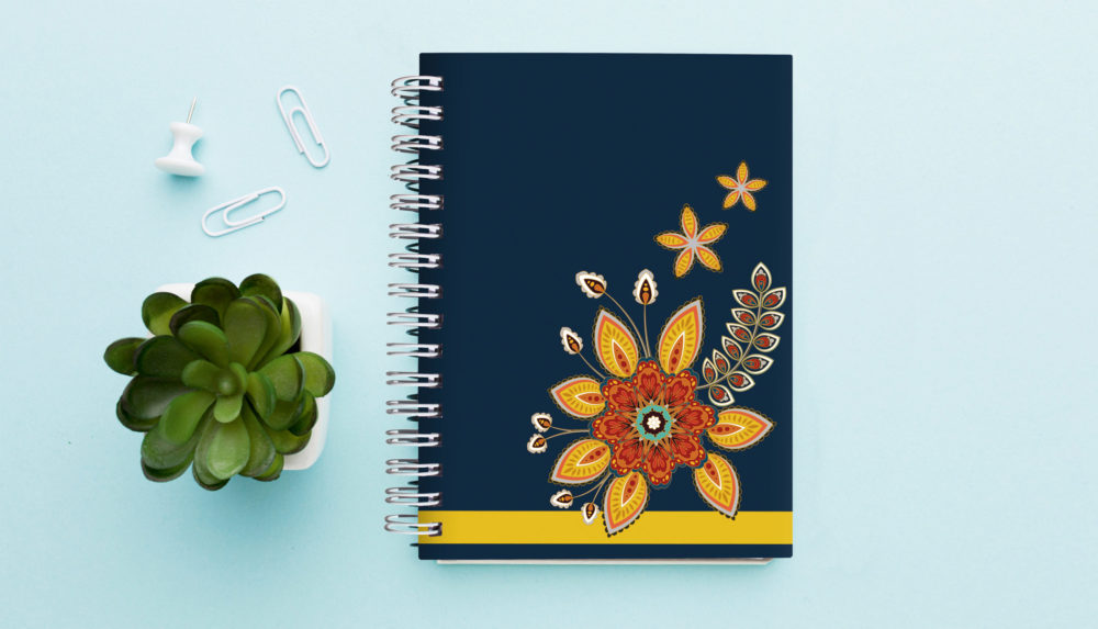 Notizbuch mit Register A-Z "Orient Flowers" auf einem Tisch mit einer Pflanze