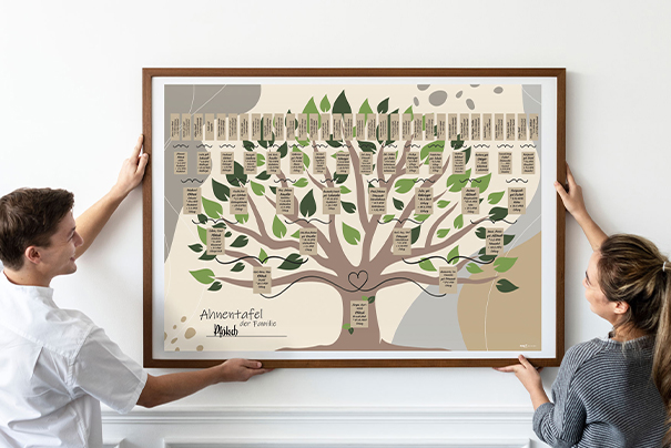 Ahnentafeln_605x404 Eine Frau und ein Mann hängen ein Bild von einer Ahnentafel auf.