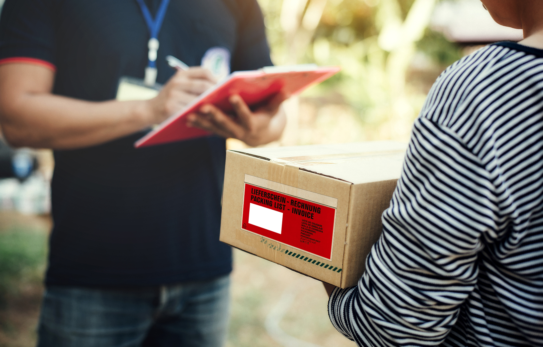 Postbote überreicht ein Paket mit einer Begleitpapiertasche